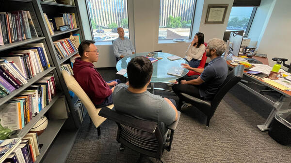 Five people meeting in office around circle table